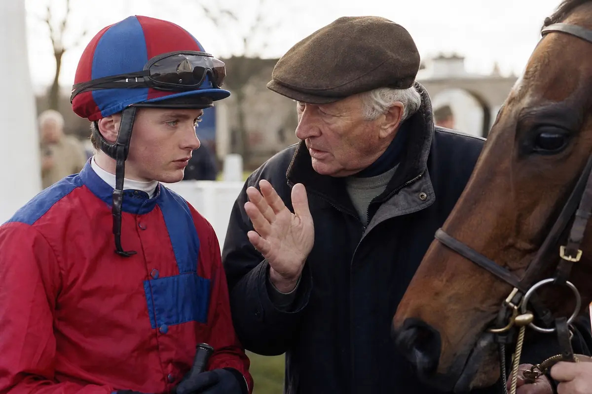 Jeune apprenti jockey qui écoute les consignes de son entraîneur avant une course
