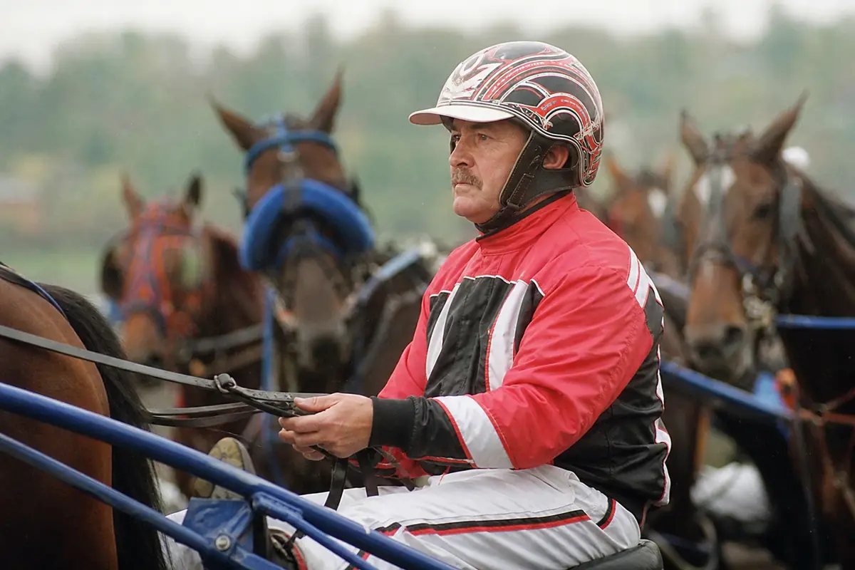 Un driver de trot attelé concentré dans son sulky avant le départ