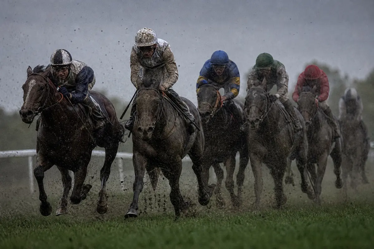 Course de galop sous une pluie battante avec des jockeys couverts de boue