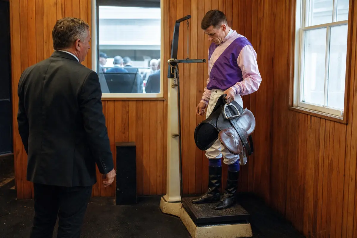Jockey sur une balance de pesée avec sa selle avant une course