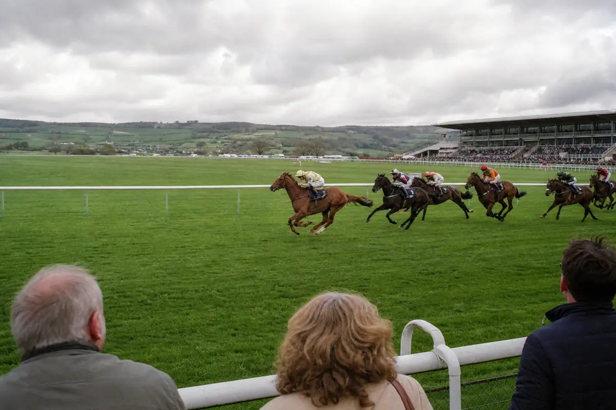 Course de galop sur un hippodrome étranger verdoyant sous un ciel nuageux