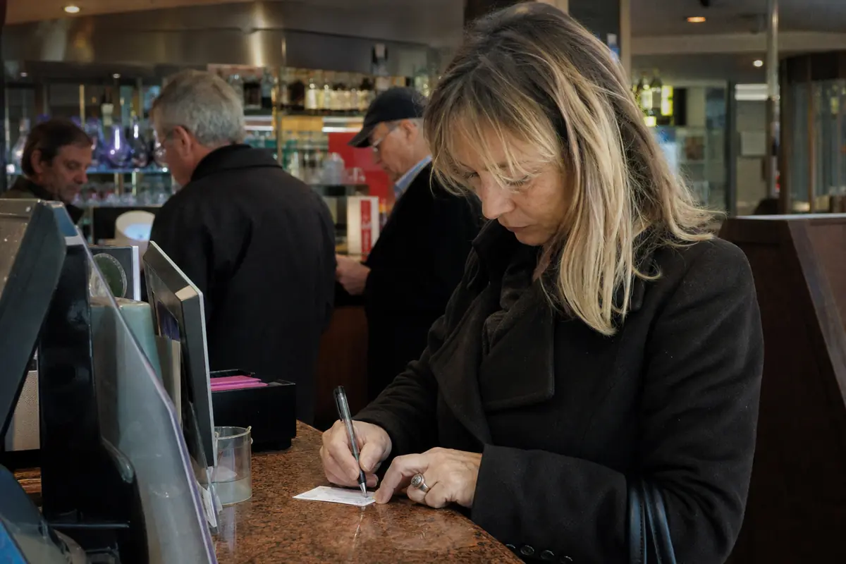 Une femme remplit un ticket de jeu au comptoir d'un café