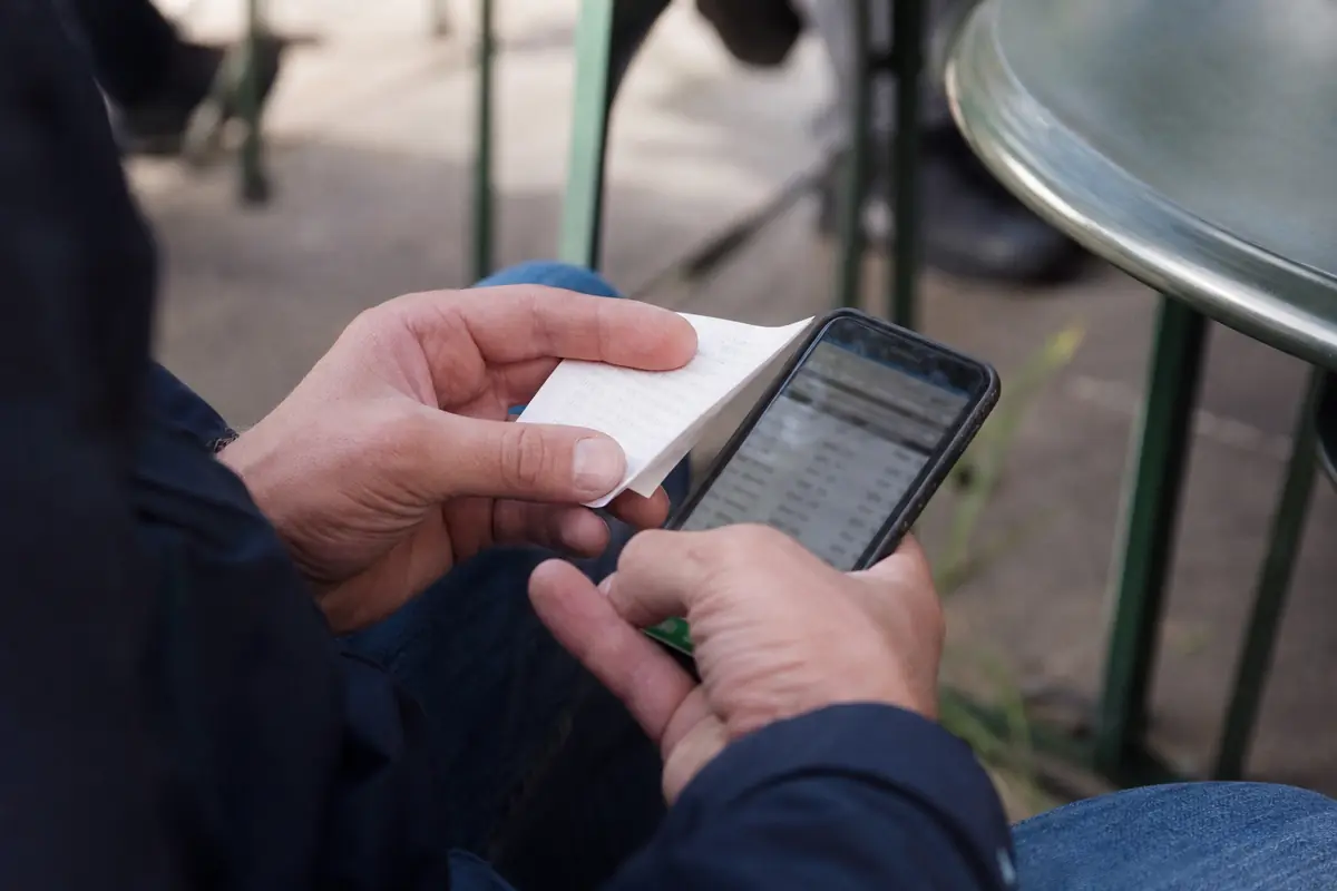 Un parieur vérifie son ticket en regardant les résultats sur son téléphone