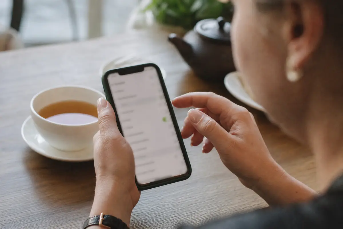 Une personne règle des paramètres sur son téléphone, assise à une table