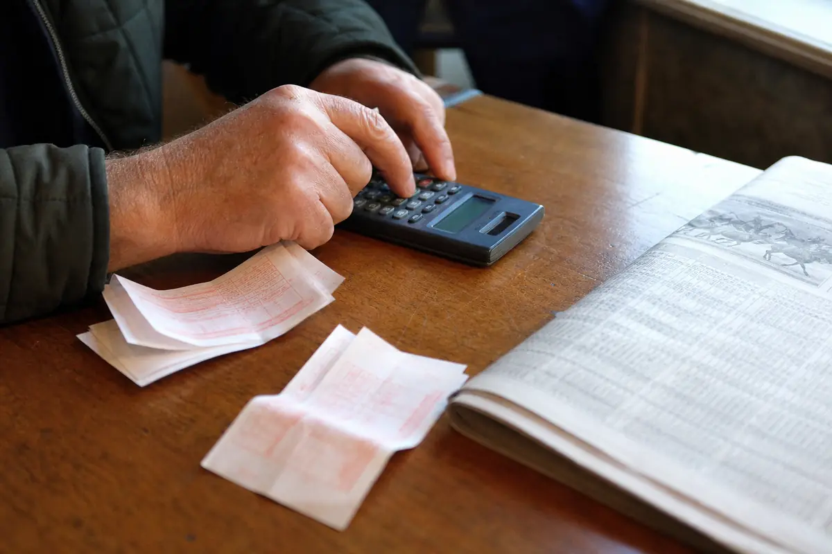Mains qui tapent sur une calculatrice à côté de tickets de jeu