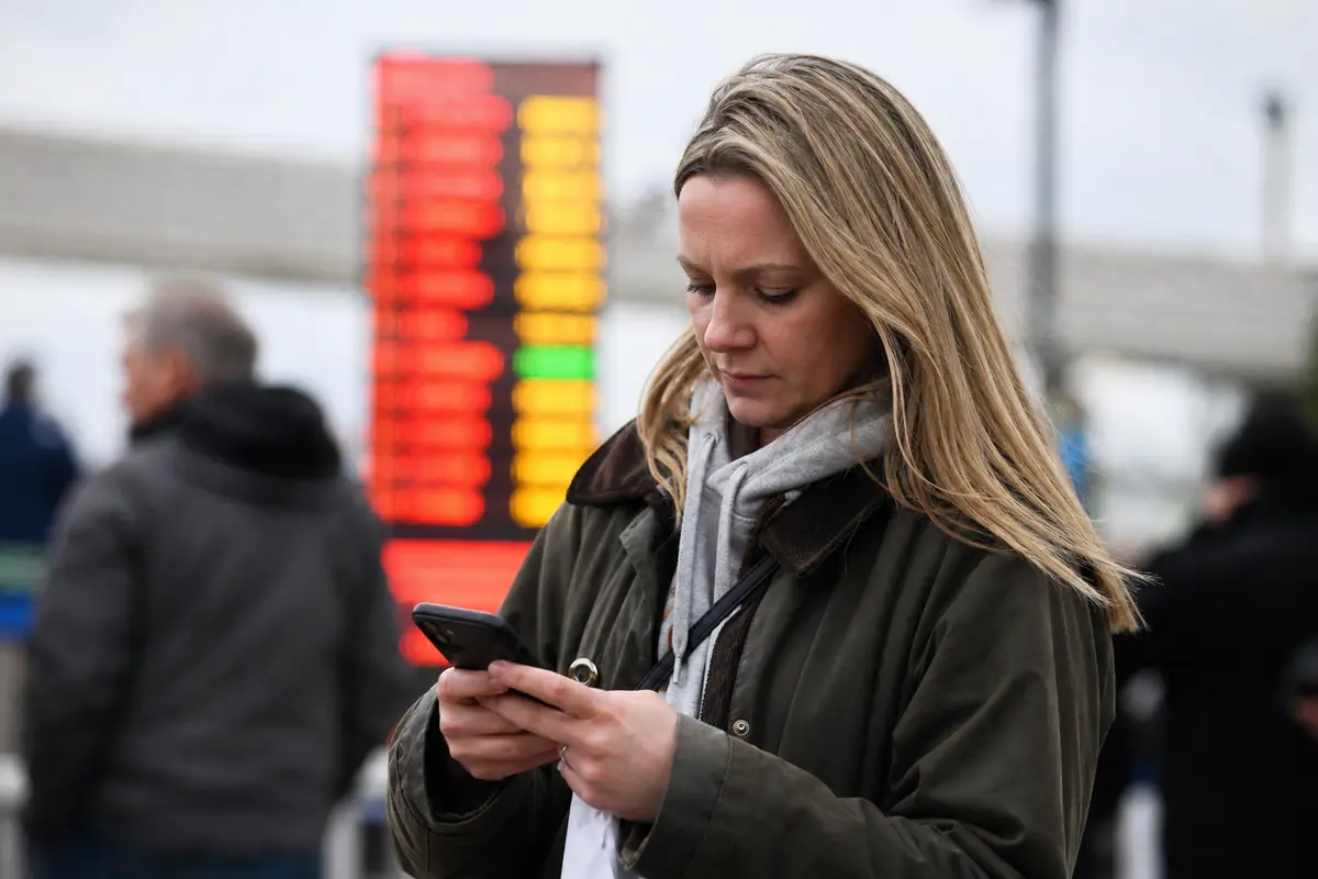 Un parieur consulte son téléphone devant un écran de cotes