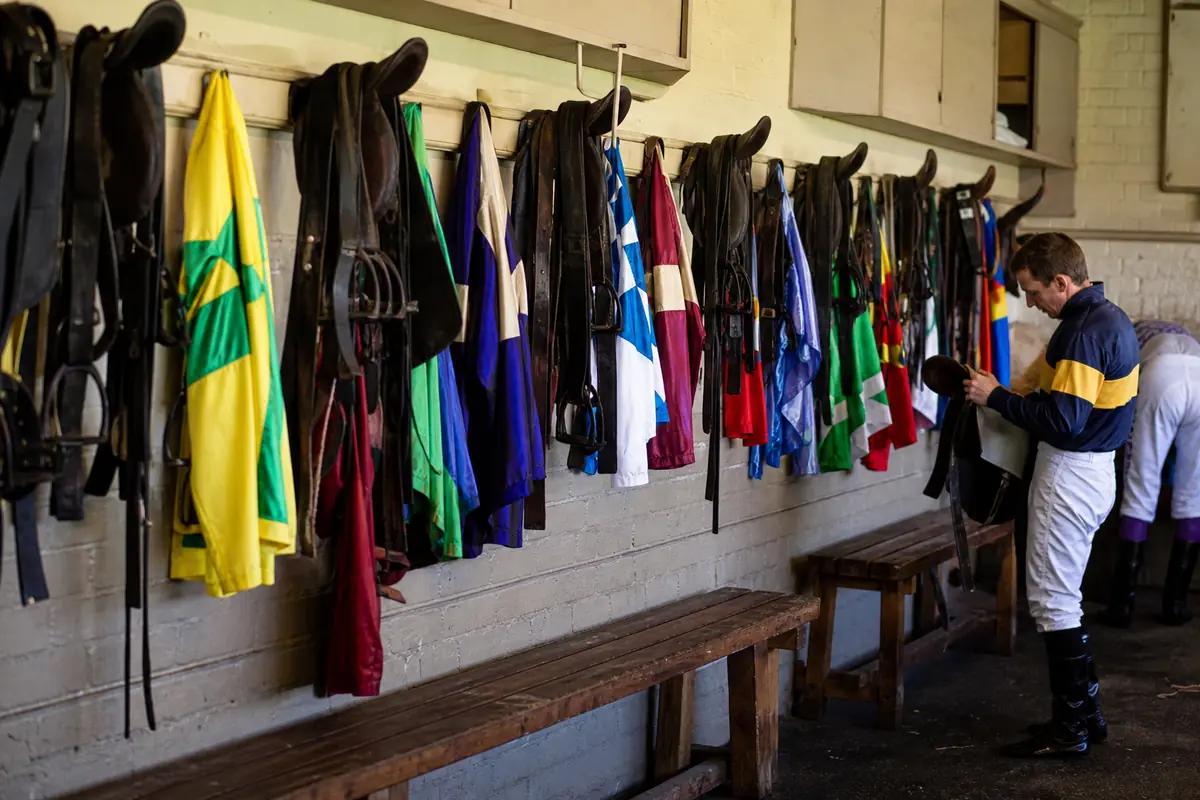 Selles et casaques colorées accrochées dans un vestiaire de jockeys