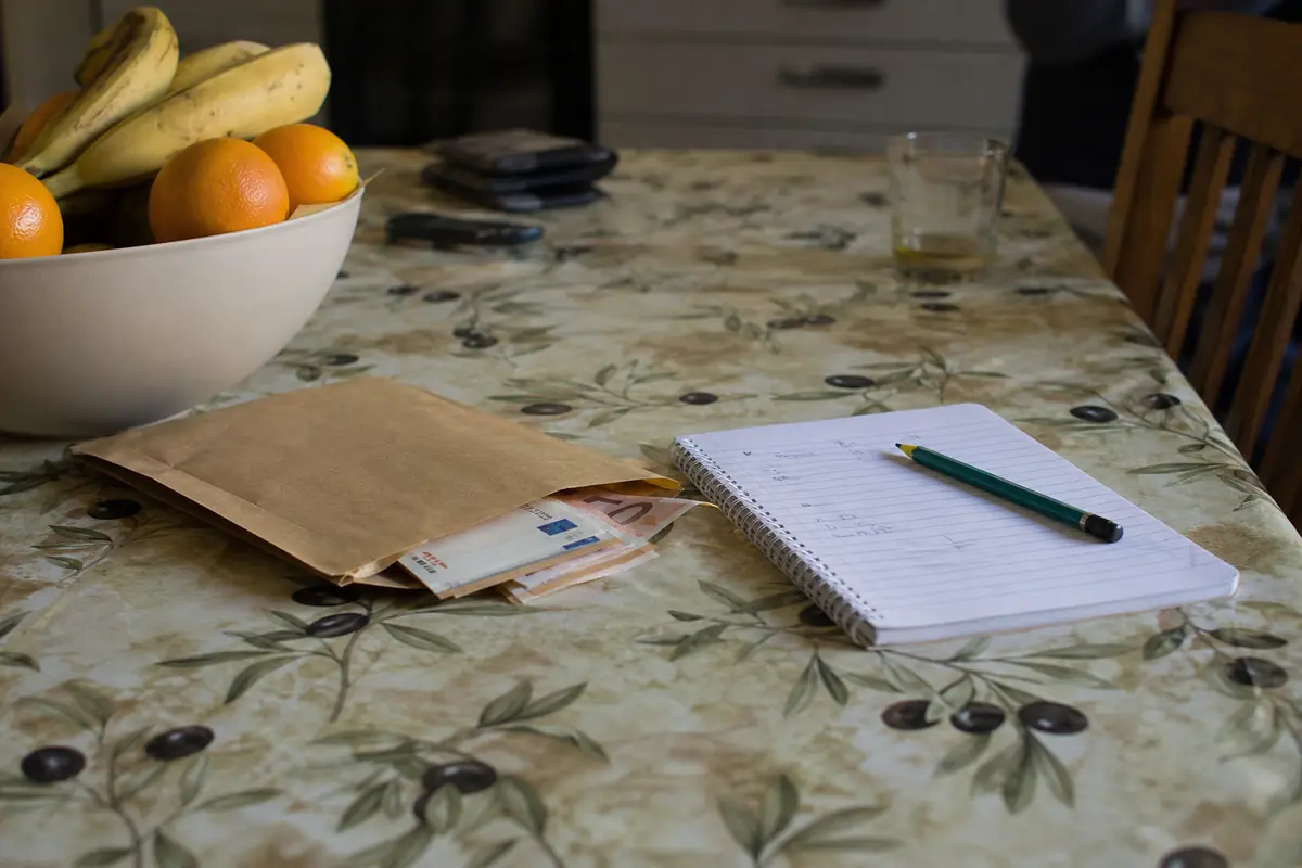 Une enveloppe d'argent liquide et un carnet de comptes posés sur une table