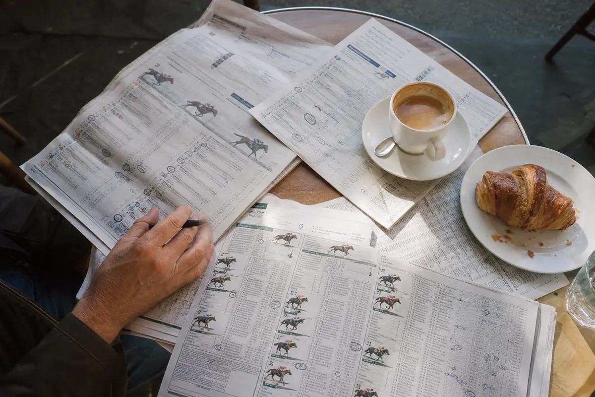 Plusieurs journaux hippiques ouverts sur une table de café