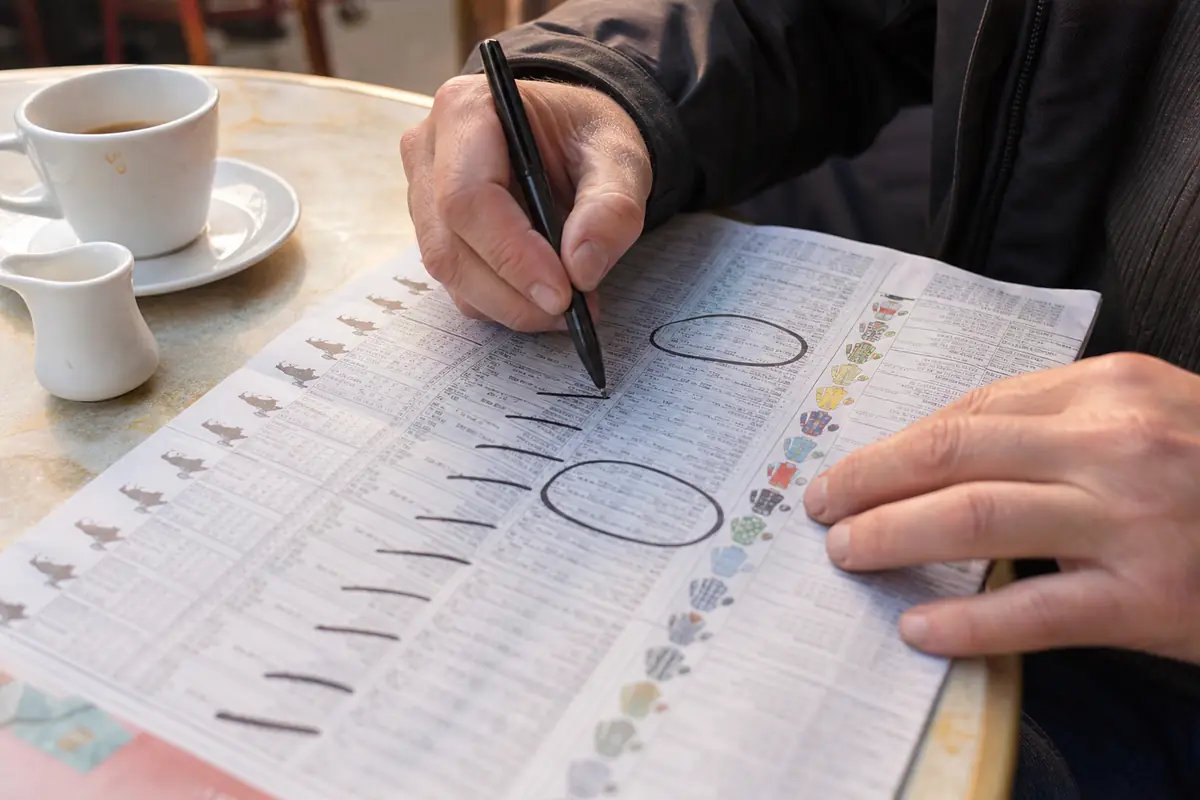 Un homme raye des courses sur un programme avec un stylo