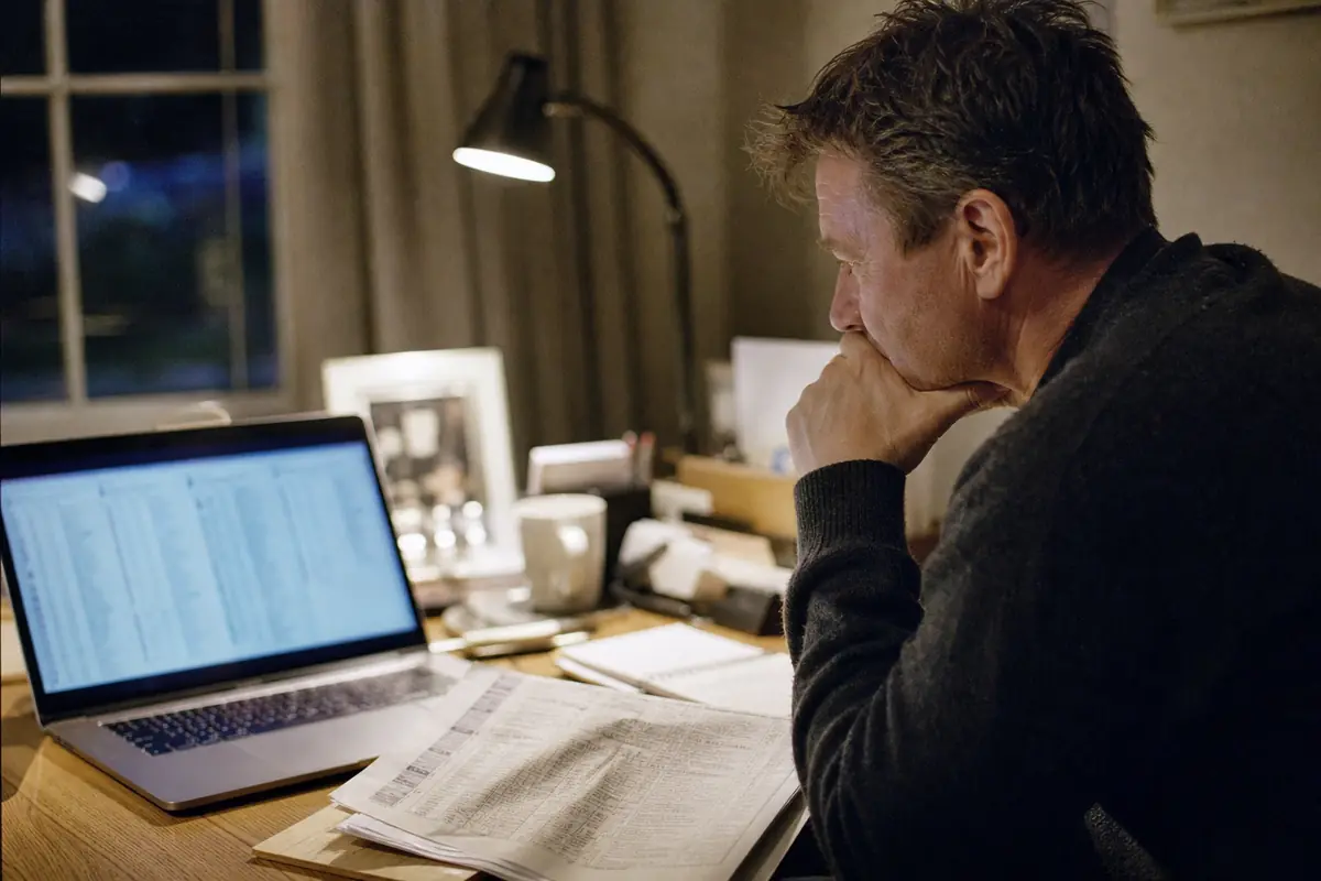 Un homme consulte des tableaux de chiffres sur un ordinateur portable